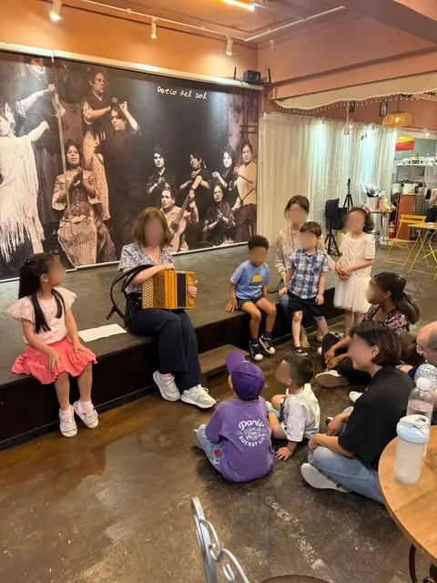 Des enfants assis par terre écoutent une accordéoniste.