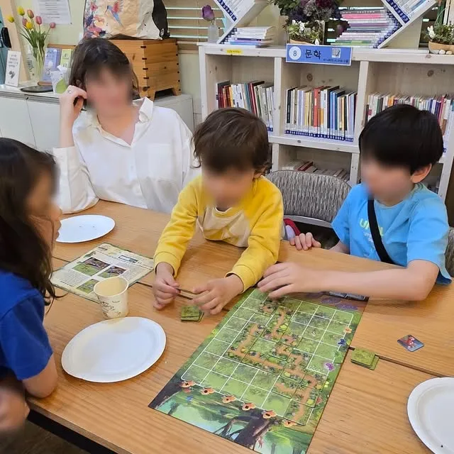 Des enfants jouent à un jeu de société autour d'une table.